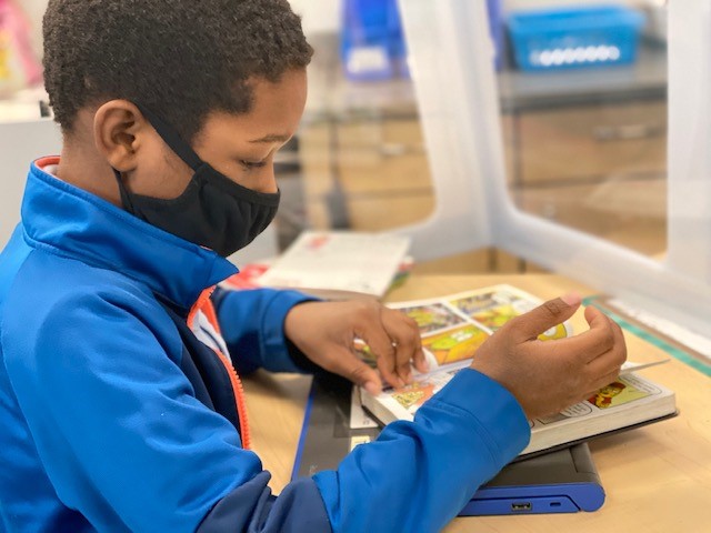 Student wearing cloth mask while leafing through graphic novel Student wearing cloth mask while leafing through graphic novel